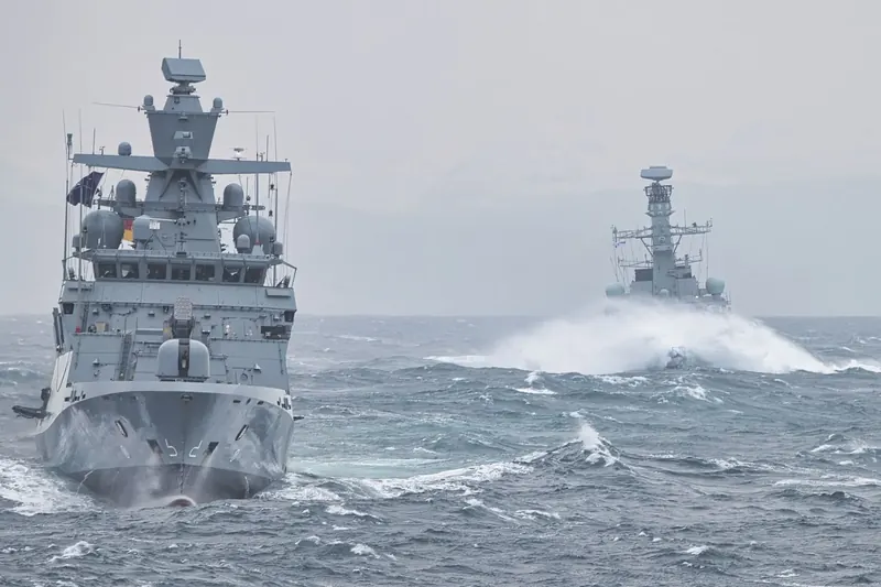 Naval warships under way in heavy seas.