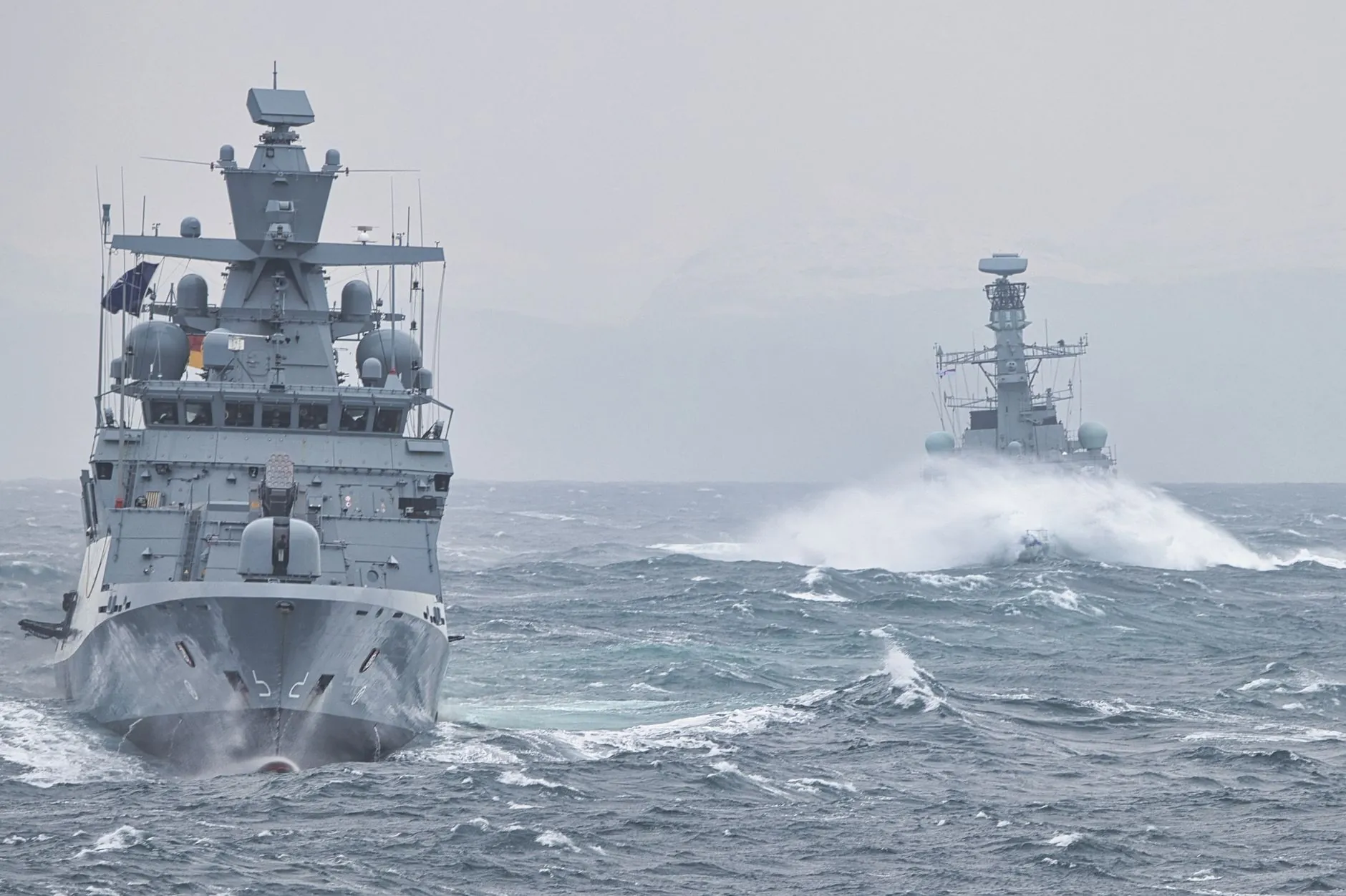 Naval warships under way in heavy seas.