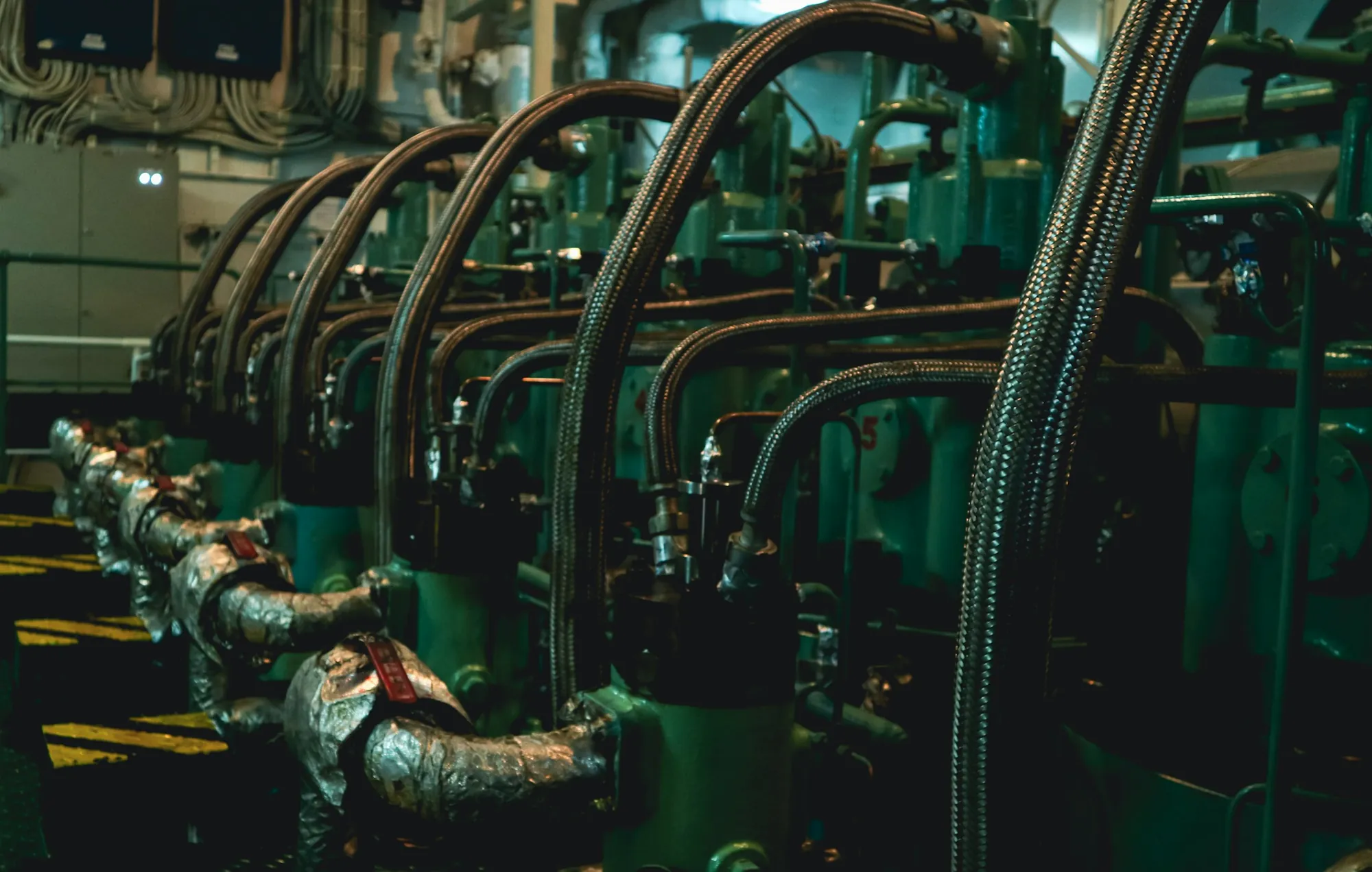A ship's main engine in the machinery space, pipework running along its length.