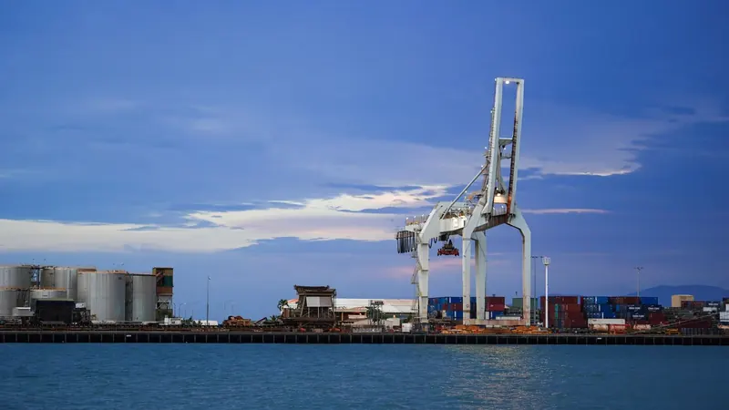An industrial port at dusk, cargo cranes along the quay.