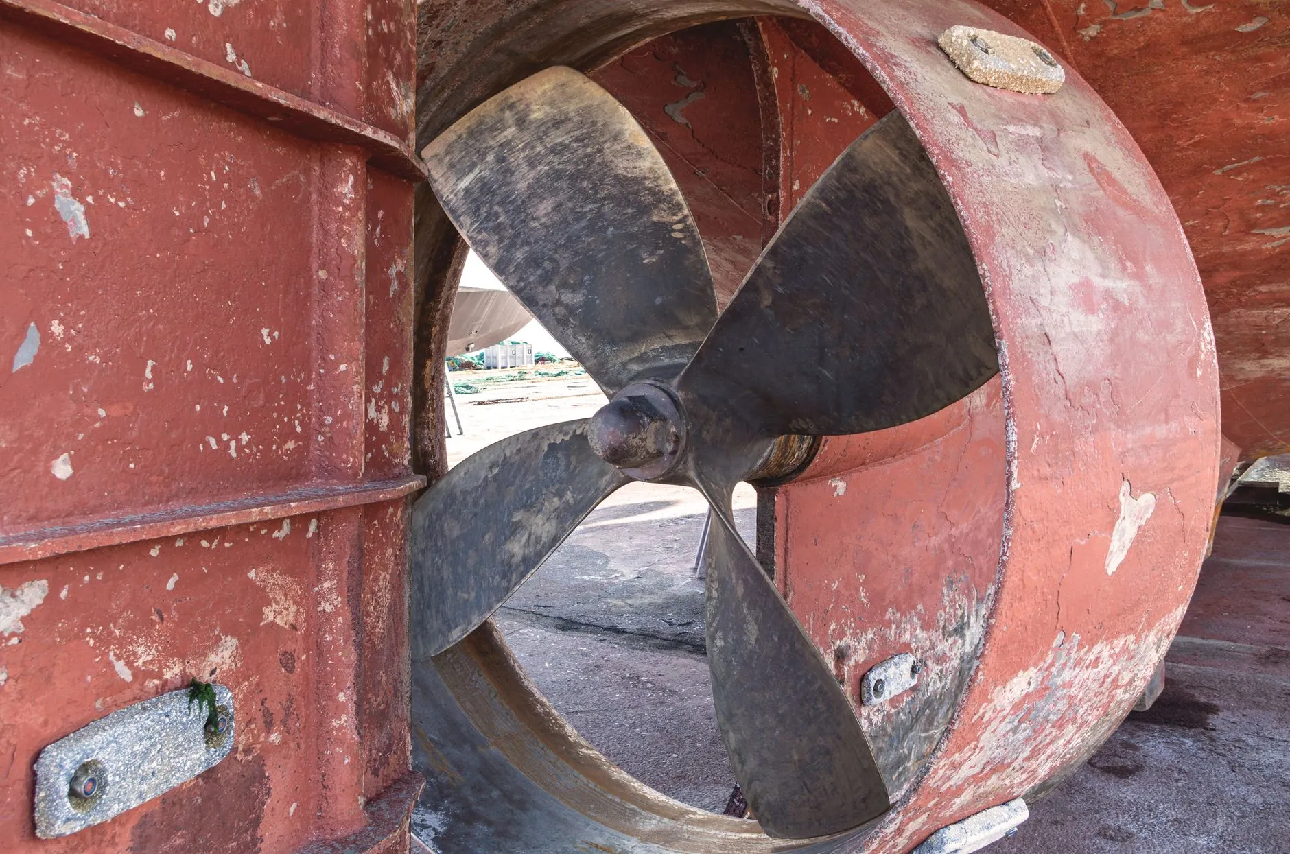 A ship's propeller in a shipyard, blades and boss seen close.