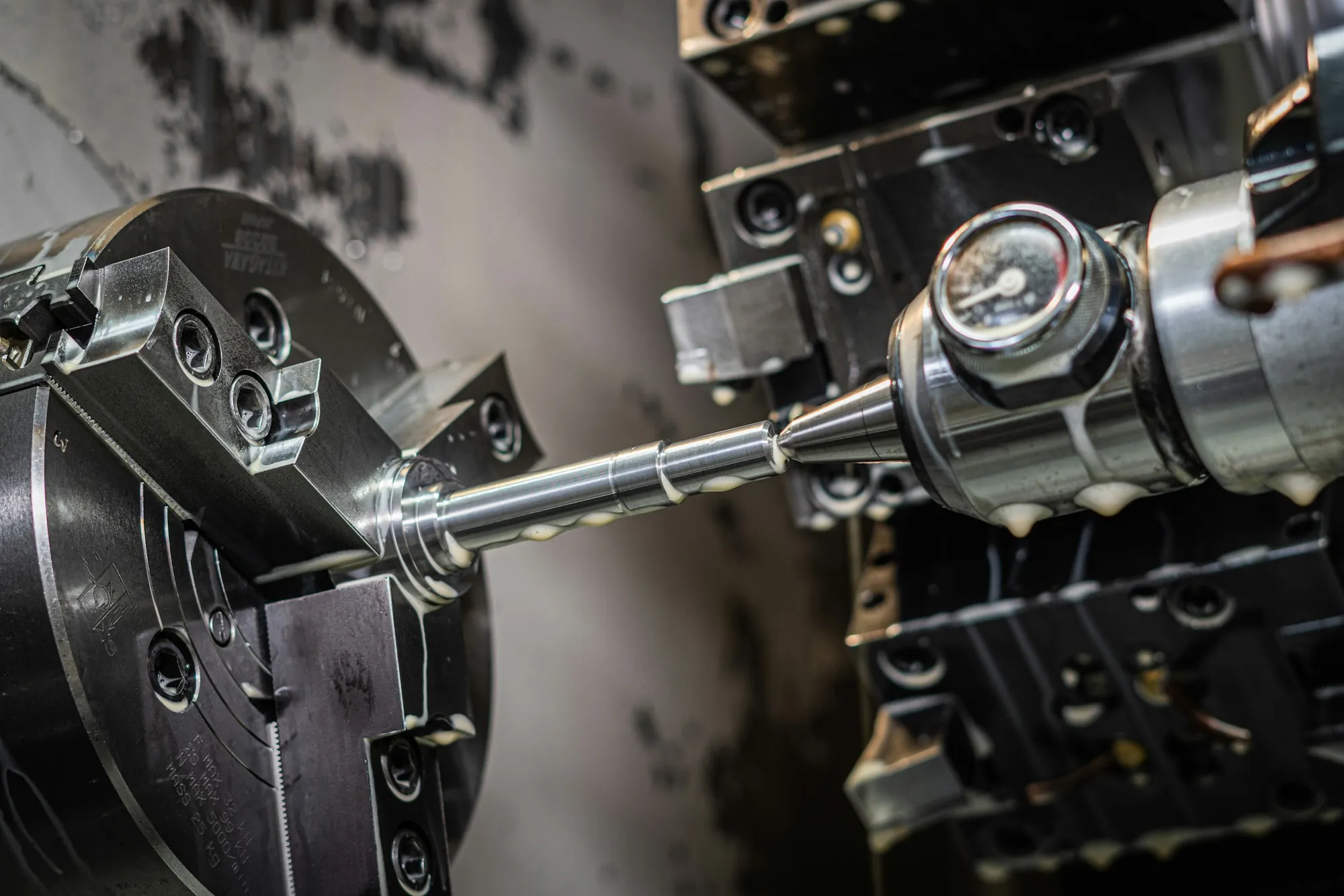 A shaft being turned on a CNC lathe, the tool engaged with the workpiece.