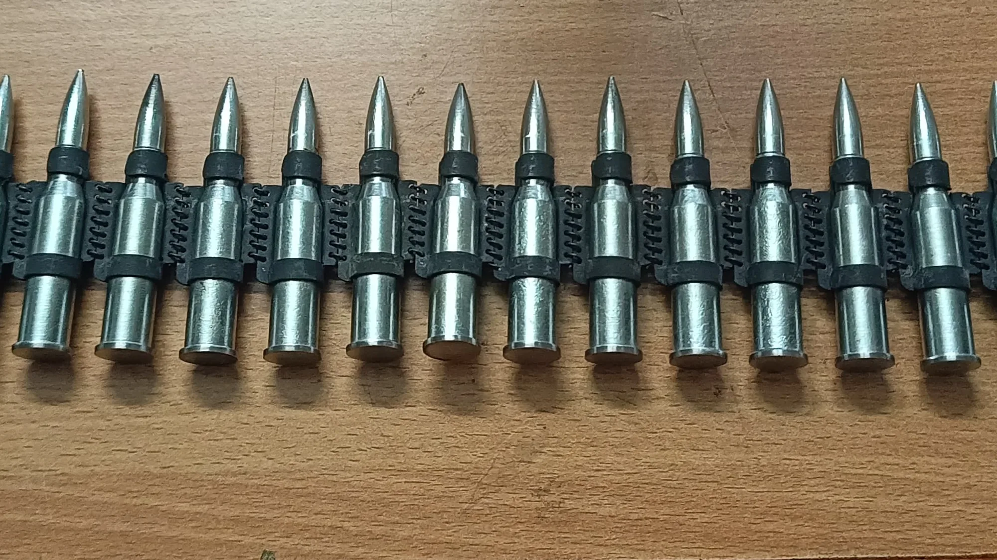 A length of 7.65 mm linked belting laid out on a bench, rounds seated in their links.