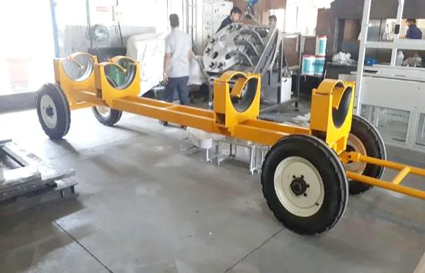 A yellow wheeled handling frame with saddle supports, inside the fabrication shop.