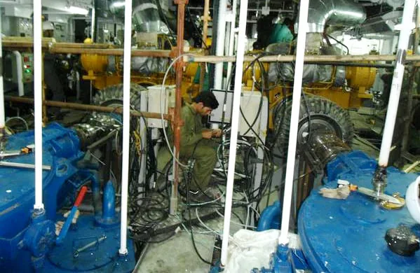 Pipework, valves and blue auxiliary machinery installed in a ship machinery space during a refit.