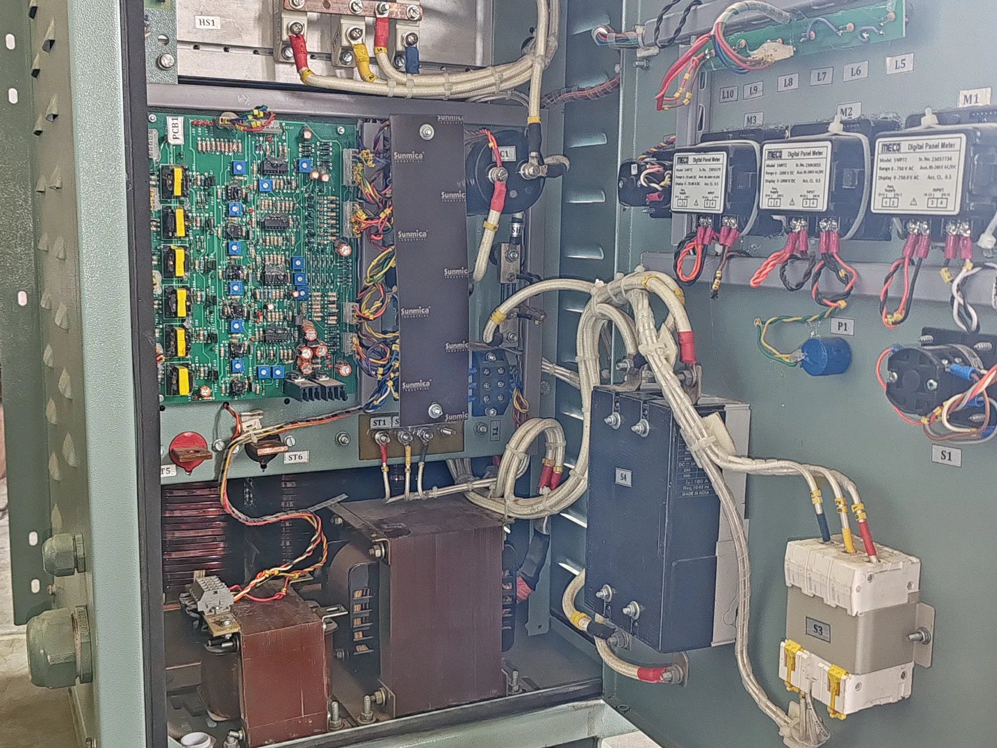 A rectifier cabinet with the door open: thyristor stack on its heatsink at the top, control board and transformers below, panel meters and terminations on the door.