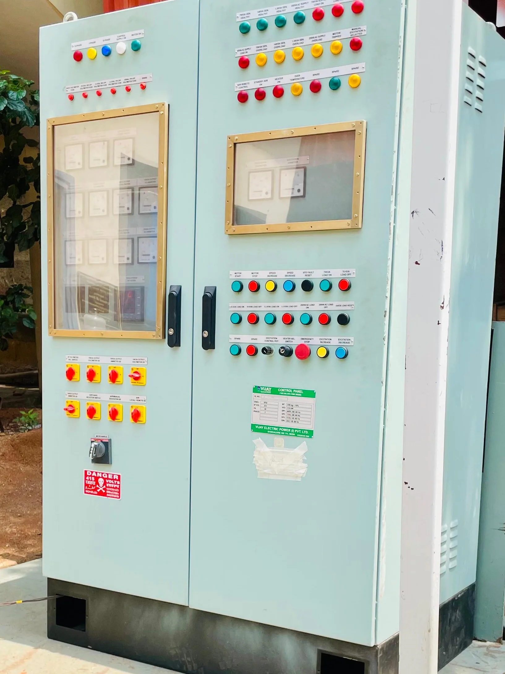 A rotary frequency converter control panel standing on its base outside a works, indicator banks and selector switches across both doors.
